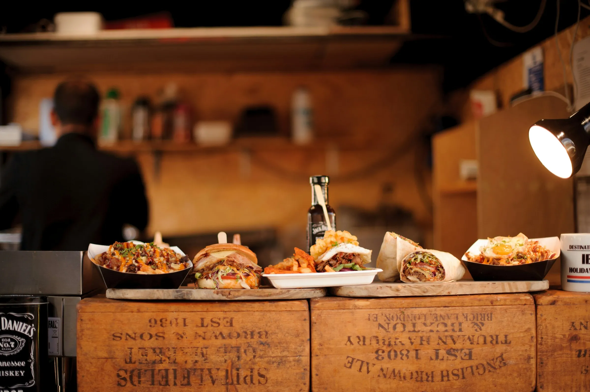 Streetfood-Stand mit frisch zubereiteten Gerichten auf einer Holztheke im warmen Abendlicht